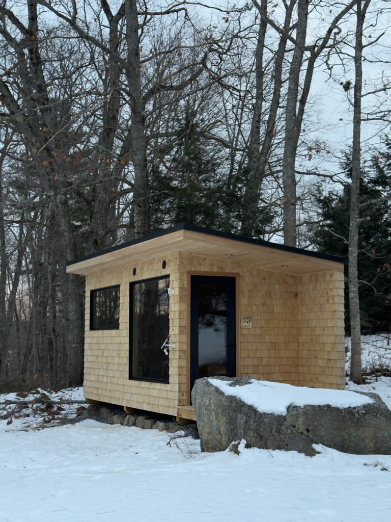 Searsmont, Maine custom sauna — full exterior in winter, cedar shingles under a black standing seam roof