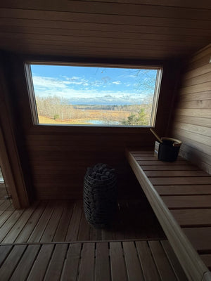 Searsmont, Maine custom sauna — hot room bench and heater with the window framing the field and pond