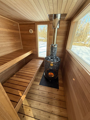 Wilton, Connecticut custom sauna — winter view across the snow-covered lawn and dry stone retaining walls, sauna at the treeline