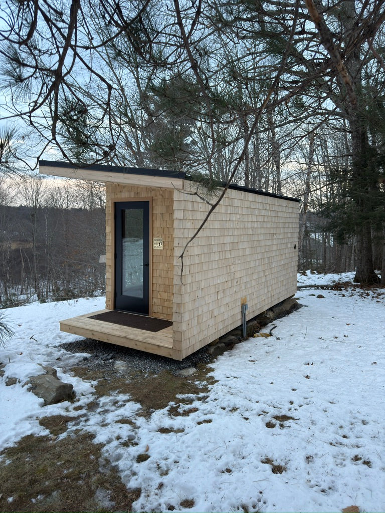 Searsmont, Maine custom sauna — exterior from the entry end, cedar shingles against snowy woods